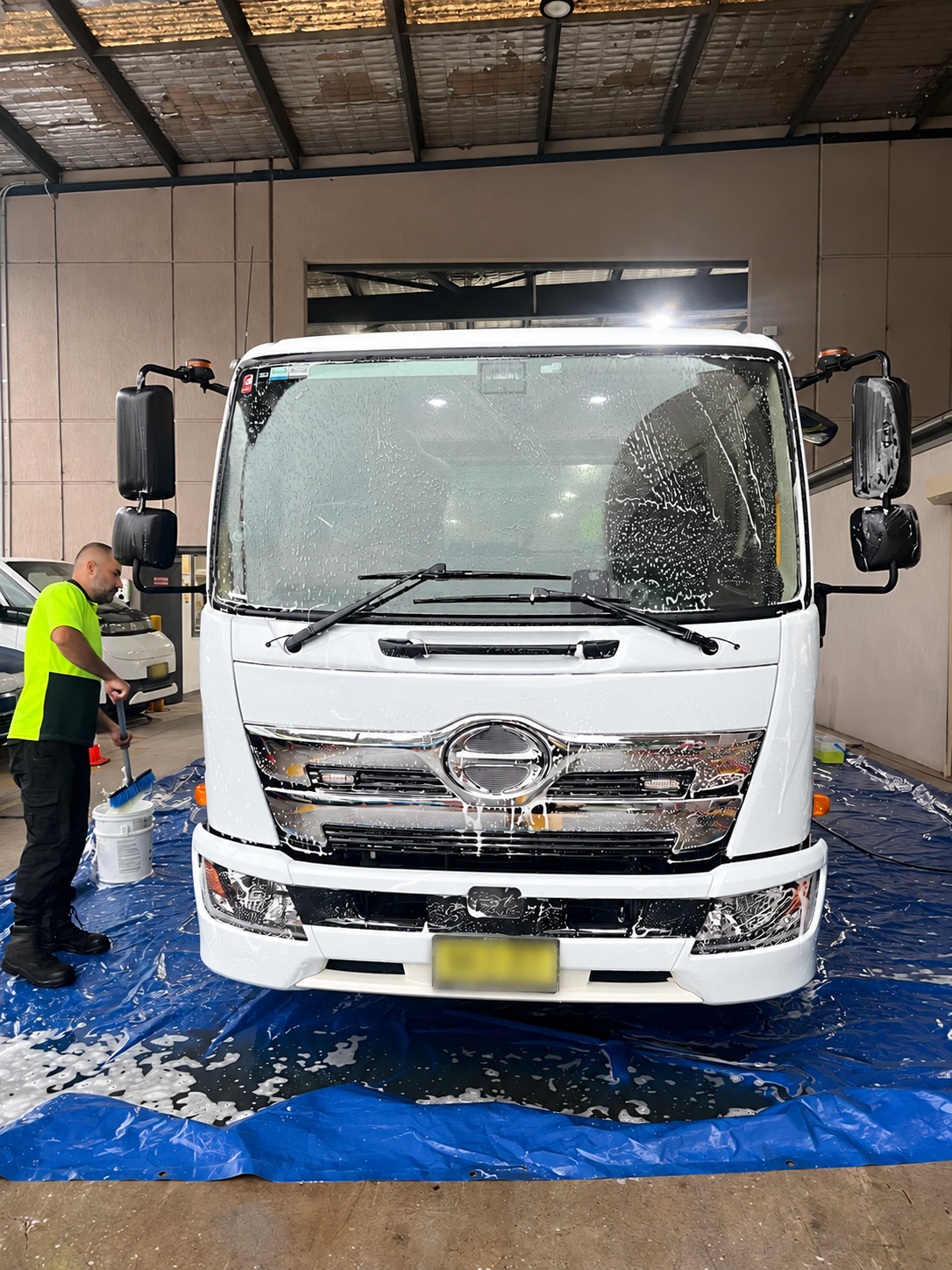 Technician washing a plain white commercial truck