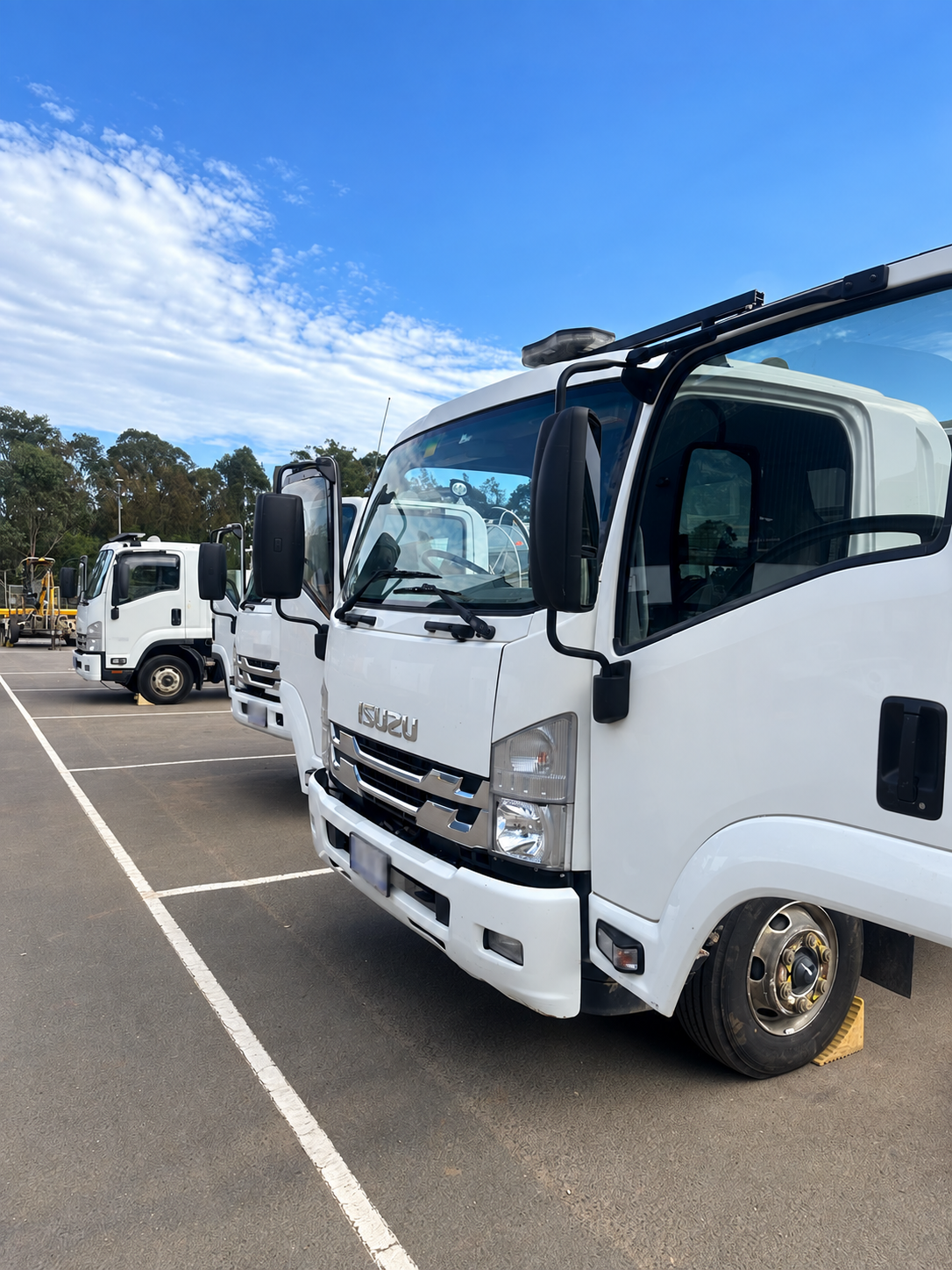 Line of plain white utility trucks with plates obscured